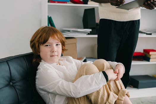 A Boy in White Long Sleeves Sitting on a Chair