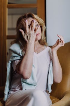 Woman in White Shirt Covering Face With Hand